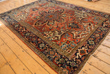 Vintage Heriz rug's dark navy border framing a cherry red floral field.