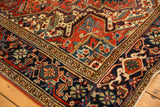 Hand-knotted Vintage Heriz rug corner with dark navy border and cherry red field patterns.