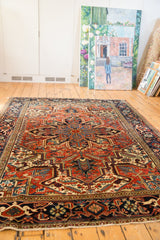 Heriz carpet corner with navy border, cherry red field, serrated leaves, and fringed edge.