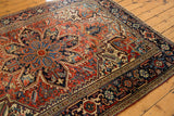 Detailed Heriz carpet field showing serrated leaves, blossoms, and florals in red, navy, and ivory.