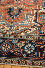Vintage Heriz carpet's intricate borders and geometric patterns in navy, red, and ivory.