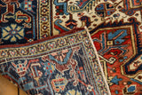 Vintage Heriz rug corner detail: hand-knotted weave, deep navy, red, ivory geometric motifs.