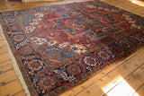 Vintage Heriz Carpet corner with a navy blue floral border, fringed edge, and red vinery field.