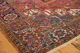 Vintage Heriz carpet corner with red, blue, gold, ivory geometric floral border and fringe.