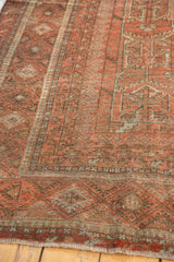 Vintage Belouch rug: multi-stripe border, serrated geometric motifs, madder red, and fringe.