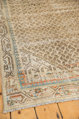 Distressed Mir Serbend rug corner, worn ivory, blue, tangerine borders, and short fringe.