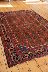 Vintage Malayer rug corner, navy border with geometric patterns, cherry red Herati field.