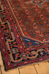 Vintage Malayer rug corner: navy border, cherry red Herati field, and aqua blue spandrel.