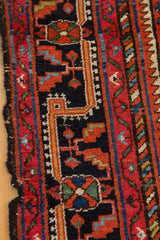 Vintage Malayer rug border detail, featuring cherry red, dark navy, gold, and aqua blue geometric motifs.