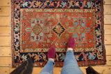 Vintage Karaja rug upper left: navy border, madder red field, light blue stepped motifs, wear.