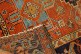 Vintage Karaja rug folded, showing hand-knotted dark blue reverse and worn geometric red pile.