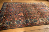 Secured side of Baktiari carpet showing cobalt blue, ivory, and madder root floral border.