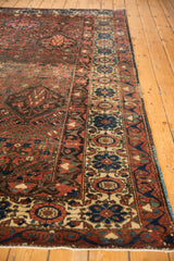 Visible wear on geometric madder red field and ivory border with cobalt blue motifs.