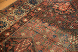 Persian Baktiari carpet with repeating panel garden motif, madder red, and visible wear.
