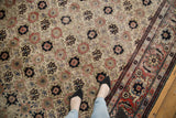 A close view of the distressed Veramin carpet's allover floral pattern and decorative red Herati border.