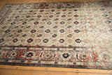 Angled view of a distressed Veramin carpet showing wear across its floral ivory field and red border.