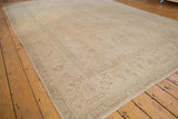 Distressed Sivas carpet corner showing faded ivory, sand, floral motifs, faint foundation, and fringe.