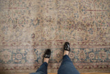 Feet on distressed vintage Sparta carpet; palmette border and tree-of-life motif in muted antique ivory, blue.