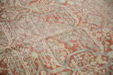 Distressed Mahal carpet texture with faded cherry red and dusty blue botanical motifs.