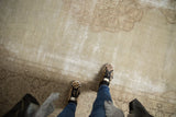 Worn ivory field and faded pale coffee brown floral vinery on a distressed vintage Tabriz carpet.