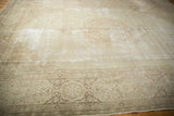 Decorative distressed corner of a vintage Tabriz rug, with pale brown curvilinear borders and ivory field.