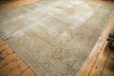 Corner of a distressed Tabriz carpet, showcasing ivory field wear and pale coffee brown scrolling vinery border.