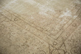 Corner of a distressed vintage Tabriz rug, highlighting faded ivory and pale coffee brown vinery.