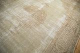 Faded ivory field and ornate brown vinery border with worn texture on a vintage Tabriz rug.