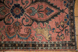 Dusty raspberry Lilihan rug detail: Manticore motif, scrolling florals, and tattered corner.