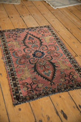 Partially secured edge of a Persian Lilihan rug with dusty raspberry field and Manticore motif.