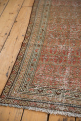 Distressed Malayer rug border detail with faded blush, beige colors, fringed edge, and worn boteh pattern.