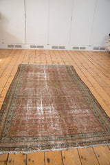 Decorative distressed texture in blush and brick red with fringed end of the vintage Malayer rug.