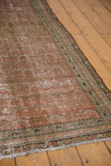 Distressed vintage Malayer rug with worn blush and red pile, faded boteh, and ornate border.