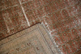 Vintage distressed Malayer rug corner revealing worn blush pile, foundation, and fringe.