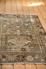 Distressed vintage Malayer rug close-up, with worn texture and faded beige, blue, brown tribal motifs.