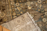 Distressed Malayer rug corner, with hand-knotted foundation, frayed white fringe, and muted colors.