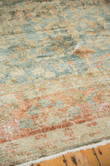 Worn texture of a vintage Lilihan rug with faded teal and terra cotta floral designs.