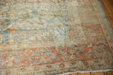 Distressed Lilihan carpet corner: worn pile, exposed foundation, and teal-terra cotta patterns.