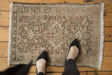 Distressed vintage Persian Karaja rug showing central medallion, geometric ivory, green, brown patterns.