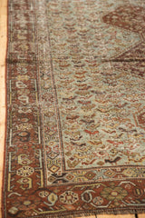 Distressed vintage Qashqai rug corner shows worn sky blue pile, bird motifs, and rust borders.