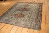 Distressed Qashqai rug corner, faded rust border, sky blue field with visible foundation.
