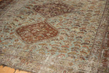Distressed Qashqai rug with rust medallion, field of blue bird motifs, and wear.