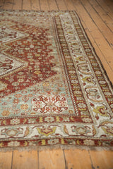 Distressed pile texture of vintage Shiraz rug, highlighting dusty powder blue, dark copper, and ivory border.