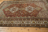 Distressed Shiraz carpet's decorative border with floral motifs and time-softened red, blue field texture.
