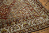 Corner of the distressed vintage Shiraz rug, showing worn copper pile and faded floral border.