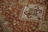 Vintage Distressed Shiraz carpet close-up: geometric medallion, scattered blossoms, and worn copper, green, and ivory tones.