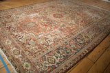Distressed vintage Heriz carpet: worn pile, geometric medallion, terra cotta, and slate blue.