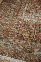 Worn texture of a distressed Heriz carpet with geometric palmettes in terra cotta and blue.