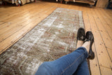 Distressed vintage Caucasian runner showing faded geometric diamond motifs and visible wear.