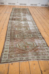 Distressed vintage Caucasian runner's end corner, showing geometric patterns, short fringe, and worn pile.